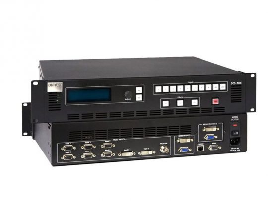 Barco DCS-200 Seamless Switcher demo device – black, rack-mounted video switcher with control buttons, display screen, and front/back DVI & VGA input/output ports; features Barco logo on the front panel.