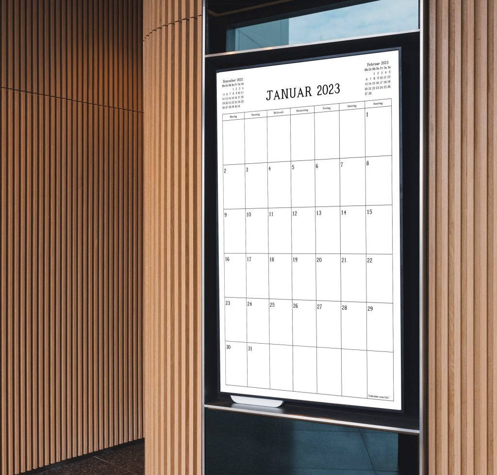 Large German wall calendar for January 2023 displayed in a modern digital office with vertical wooden slats; the calendar features bold, easy-to-read dates and blends stylish design with practical functionality.
