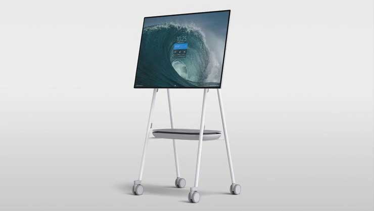 Großer, digitaler Flachbildschirm auf weißem Rollständer mit Ablagefläche, zeigt ein Wellenbild auf dem Display; ideal als Präsentationsmonitor zum Mieten oder Kaufen.