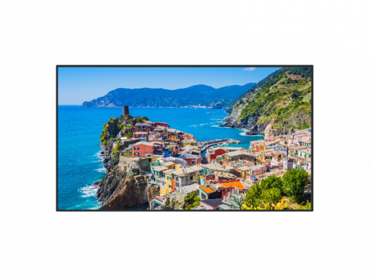 Farbenfrohes Küstendorf mit bunten Häusern auf felsigem Hang und Blick auf das strahlend blaue Meer; im Hintergrund grüne Hügel und klarer Himmel. Perfekt für Immobilieninteressierte, die ein Haus am Meer mieten oder kaufen möchten.