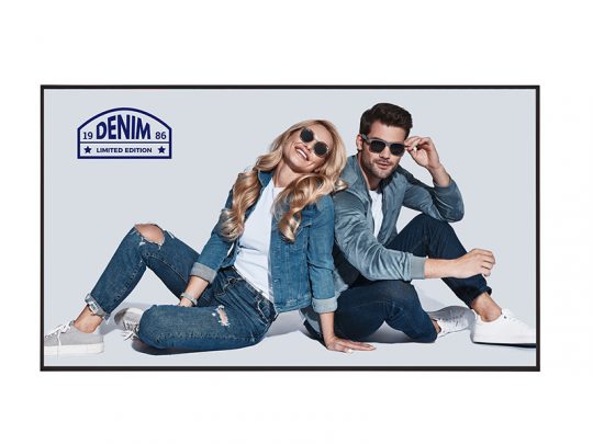 Zwei stilvolle Personen sitzen entspannt auf dem Boden, tragen lässige Denim-Outfits und Sonnenbrillen. Links oben ist das "Denim Limited Edition"-Logo eingeblendet. Das Modefoto zeigt einen Mann und eine Frau als Trendsetter für exklusive Jeansmode.