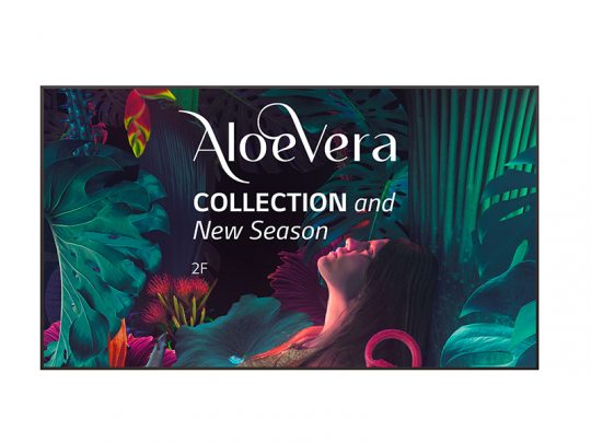 Werbeplakat für die "AloeVera COLLECTION and New Season" mit einer Frau vor großen tropischen Blättern und bunten Blumen auf dunklem Hintergrund; unten ist der Text "2F" zu sehen.