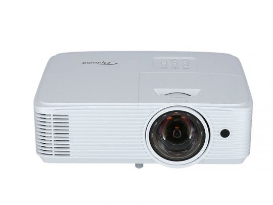 Weißer Optoma Beamer mit großem Objektiv rechts, Bedienknöpfen oben und Belüftungsgittern links, vor neutralem Hintergrund fotografiert.