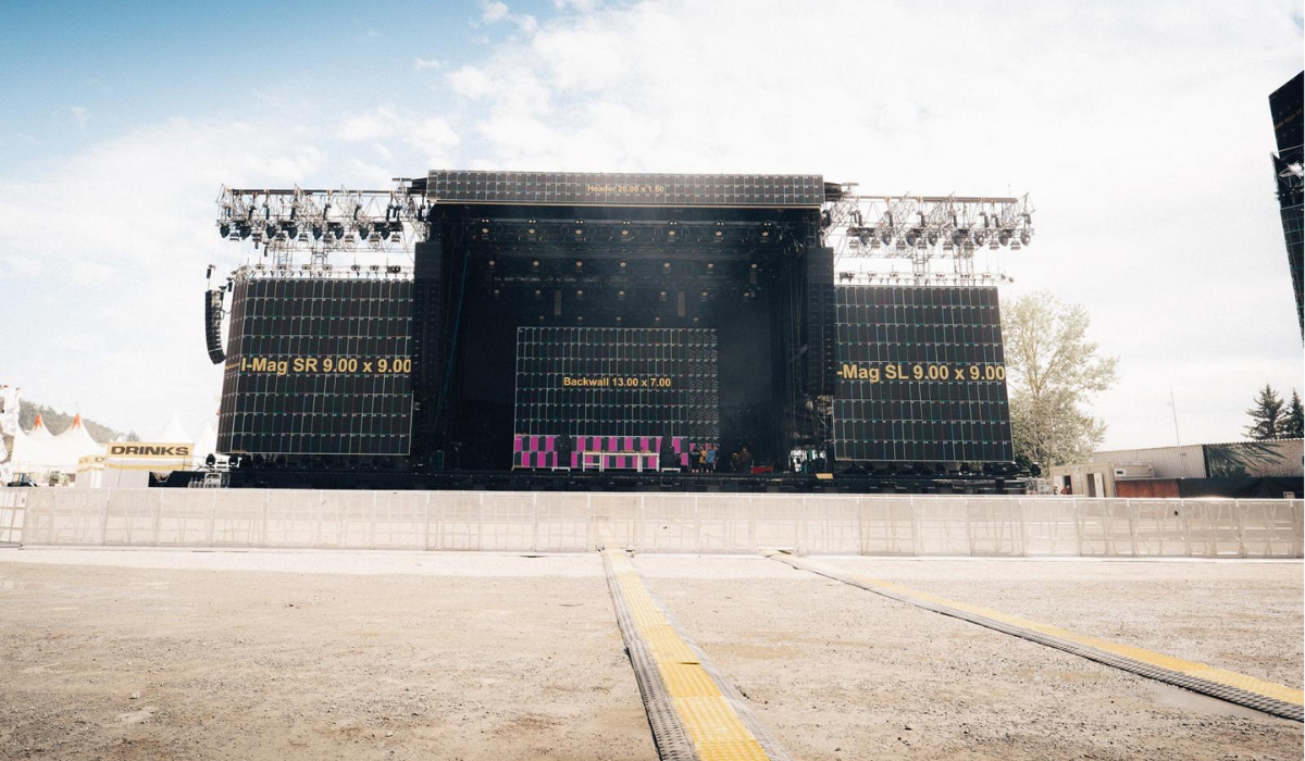 LED Wand mieten: Große Open-Air-Konzertbühne mit LED-Wänden, Lichttechnik und Absperrgittern in freiem Gelände, keine Personen.